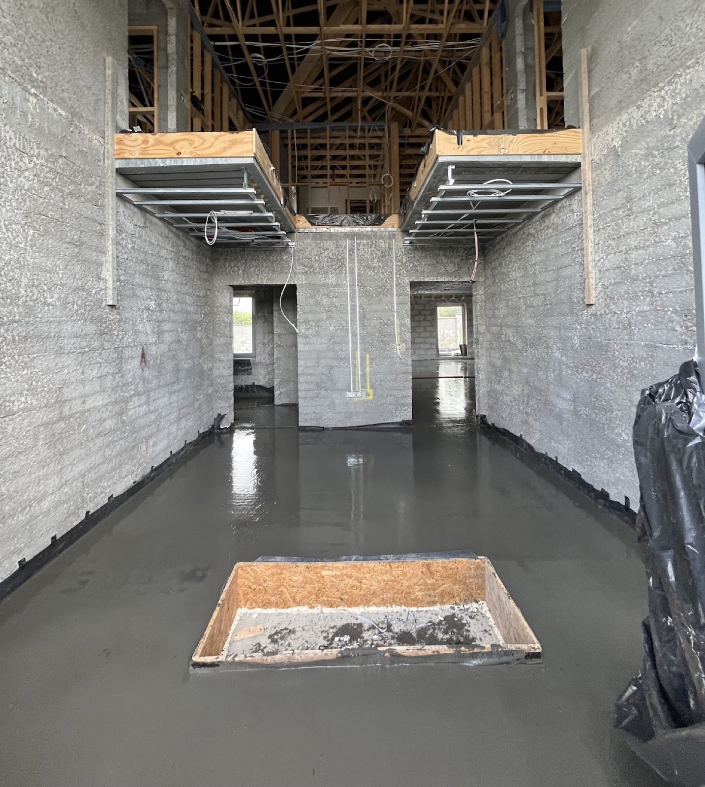 Liquid screed flooring installation in double-height hallway with mezzanine