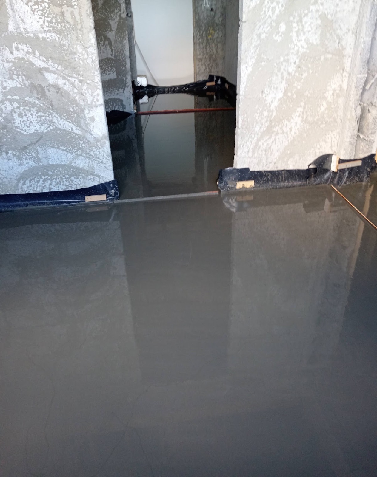 Liquid screed poured along apartment corridor floor