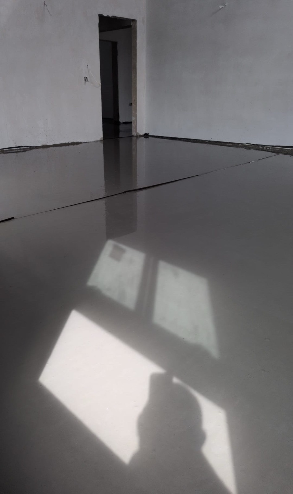 Finished liquid screed floor reflecting natural light through doorway