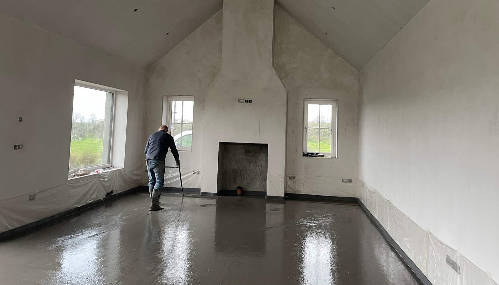 Liquid screed flooring installation in vaulted living room with fireplace